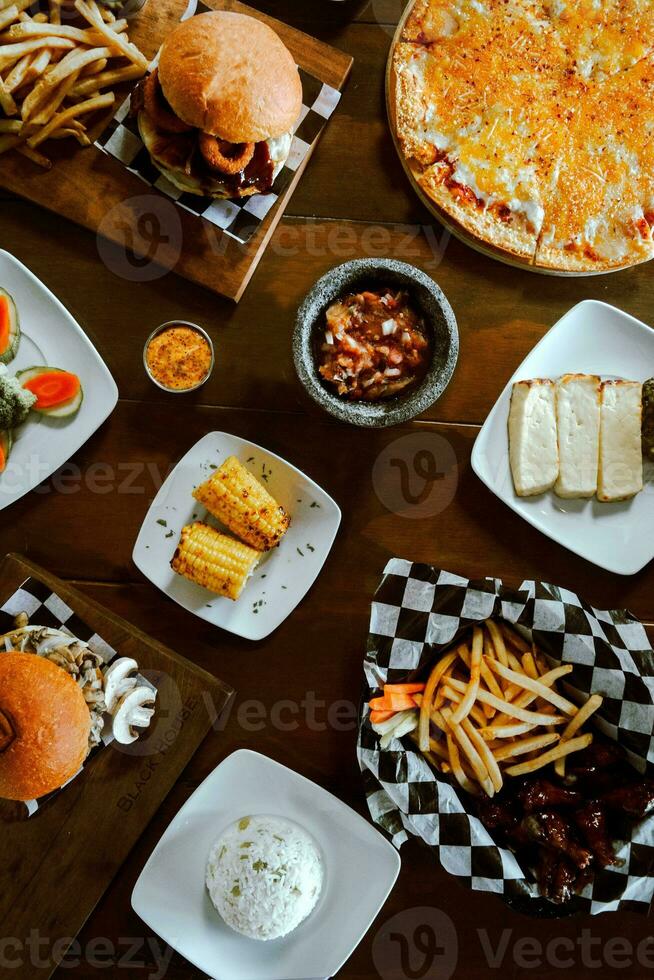 Top view of a variety of fast food on a wooden table. photo
