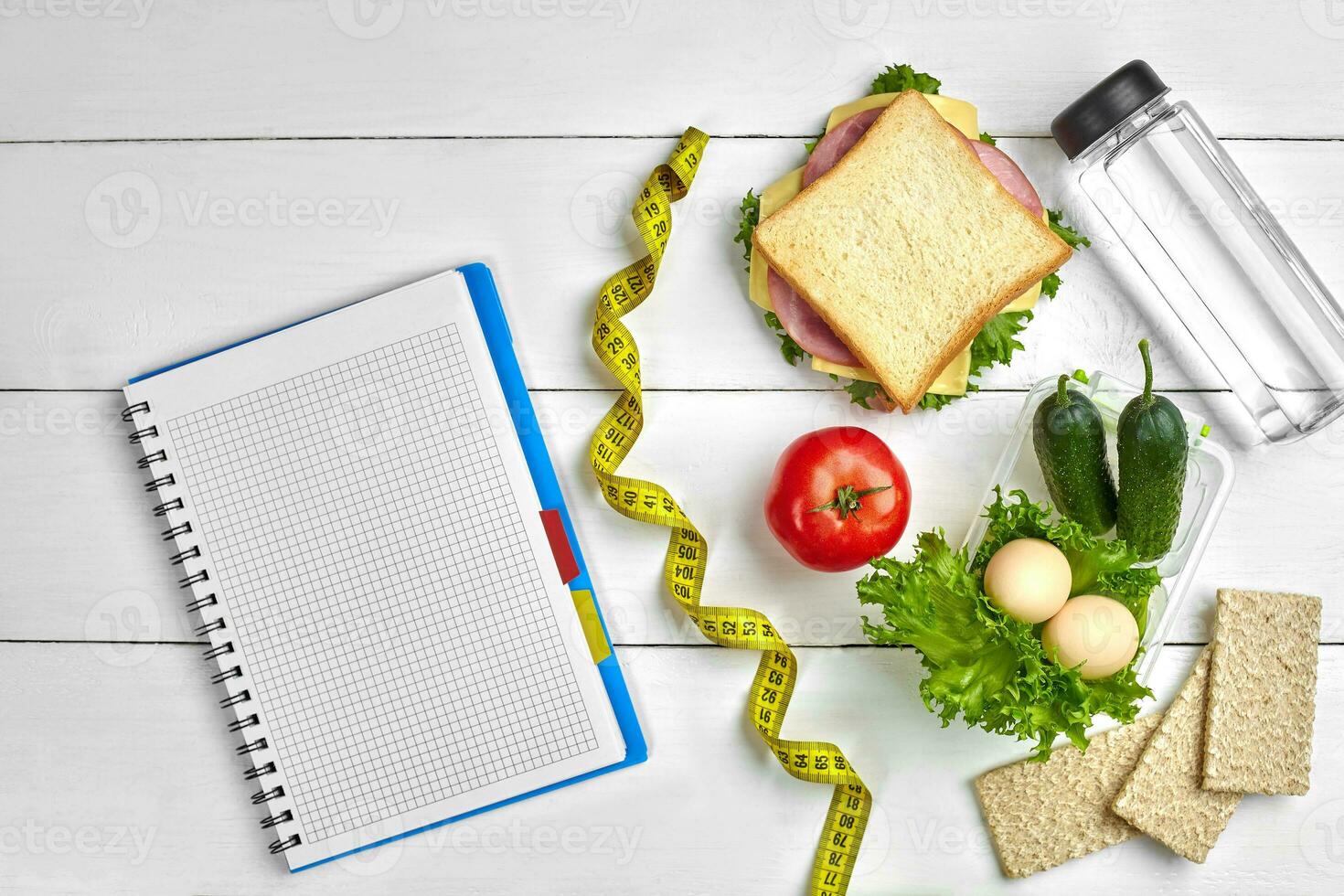Healthy lunch in office at workplace or home. Whole-grain sandwich with ham and fresh vegetables and bottle of water. Top view, flat lay on wood photo