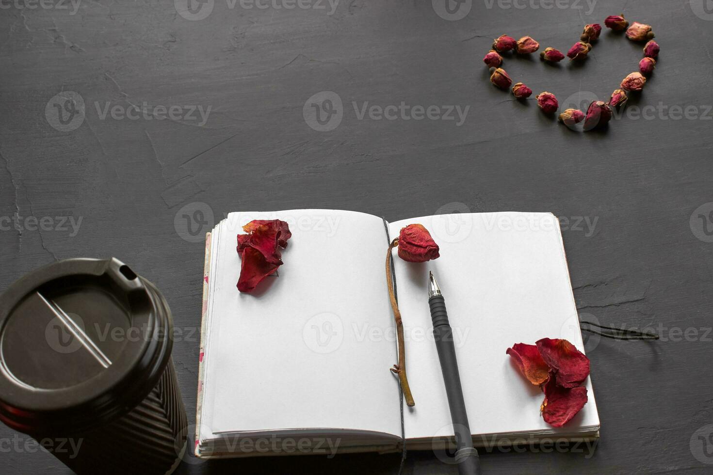 Top view of an empty notebook, scrapbook accessories and a cup of coffee on a black background. photo