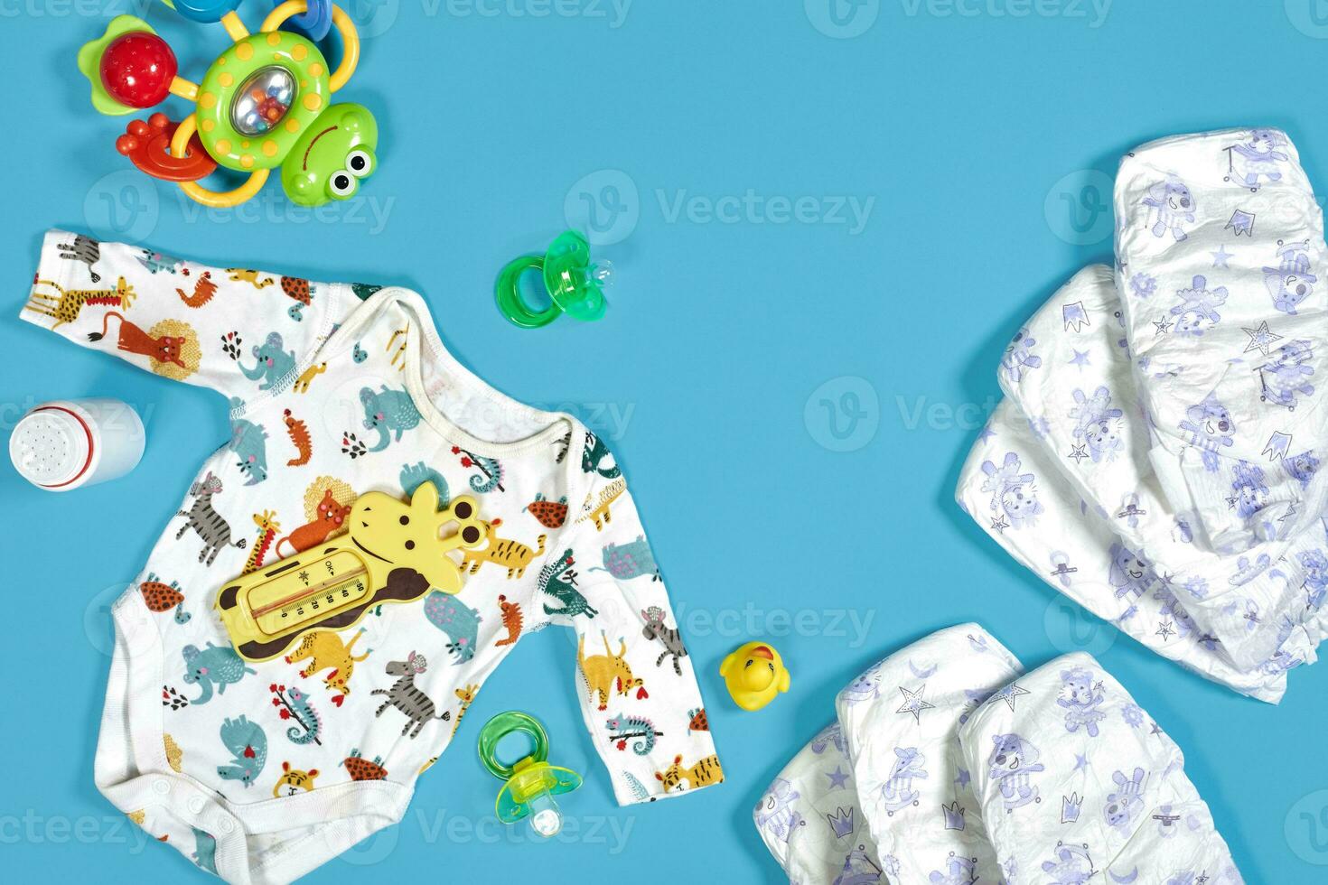 Babies goods cloth diaper, baby powder, nibbler, cream, teether, soother, baby toy on blue background. Copy space. Top view. photo