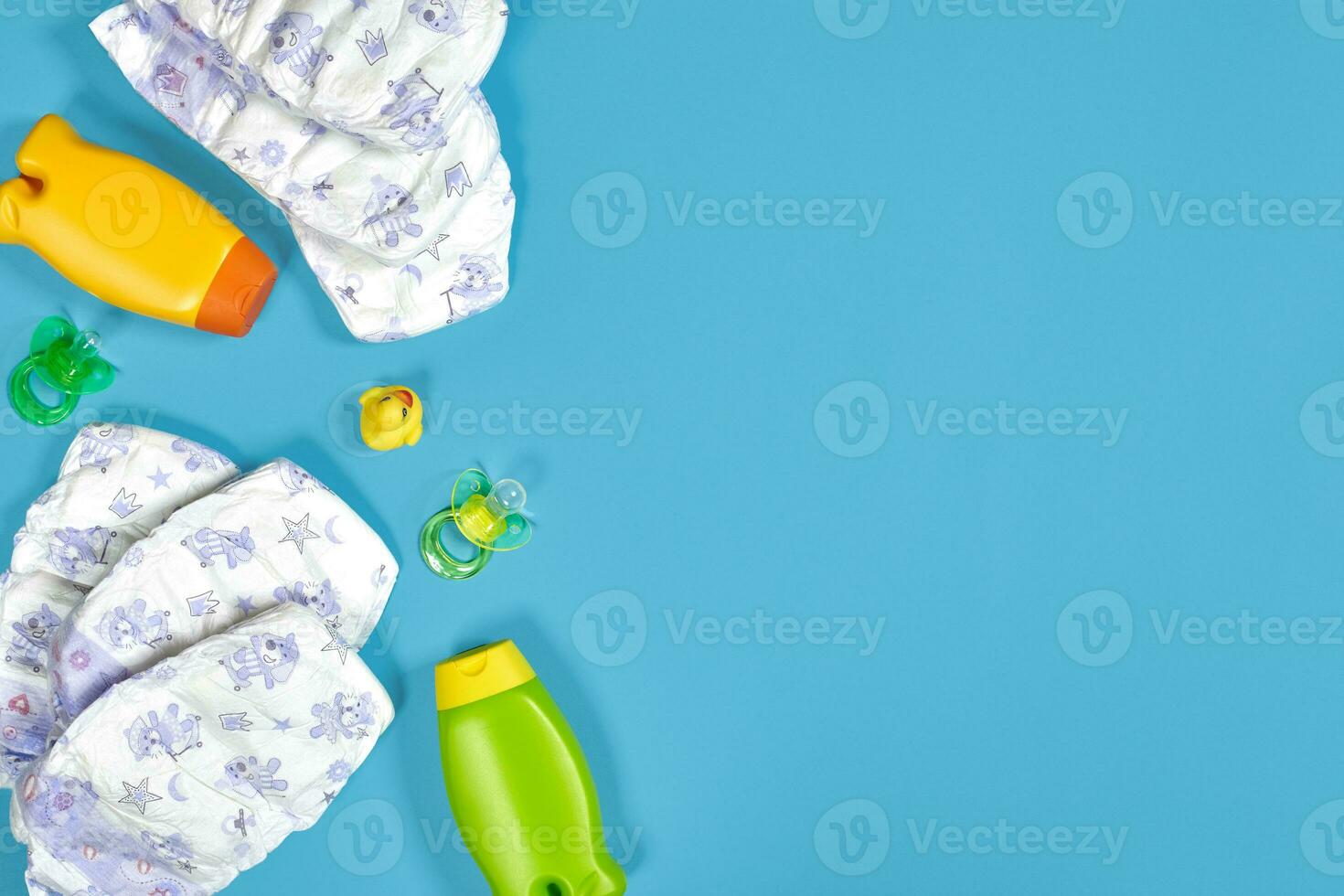 Baby care with bath set. Nipple, toy, diapers, shampoo on blue background top view mockup photo