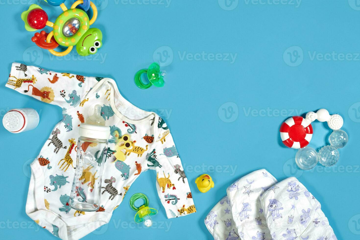 Babies goods cloth diaper, baby powder, nibbler, cream, teether, soother, baby toy on blue background. Copy space. Top view. photo