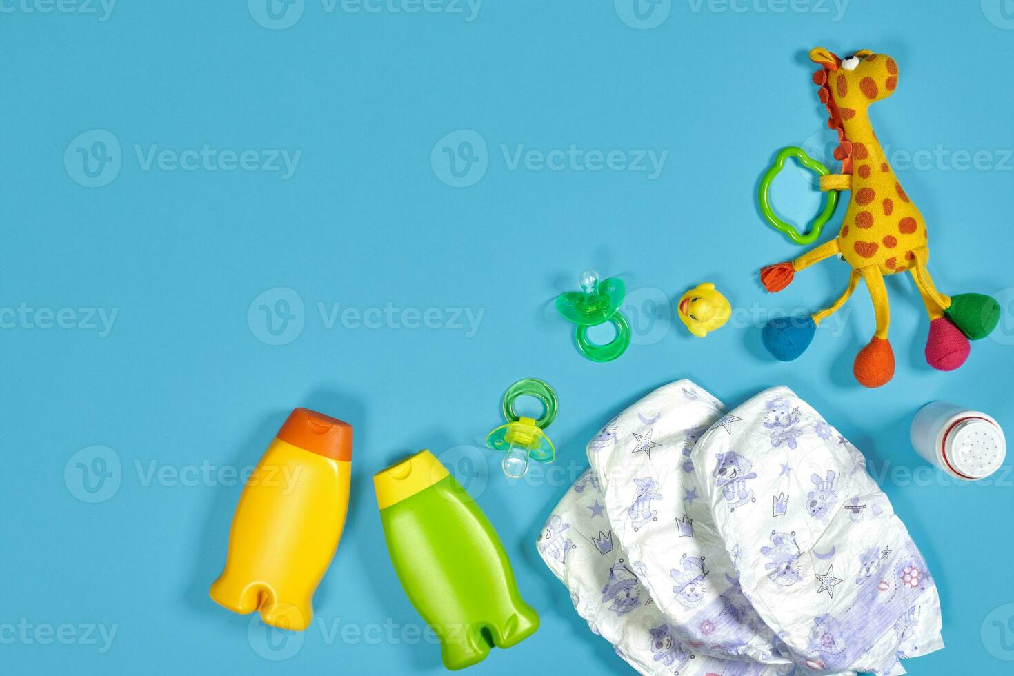 Baby care with bath set. Nipple, toy, diapers, shampoo on blue background top view mockup photo