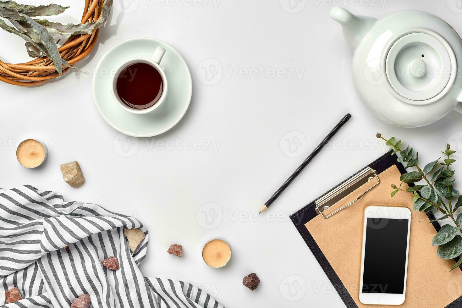 Notepad with pen and cup of tea on white table. Working space. Handmade. Top view, flat lay. photo