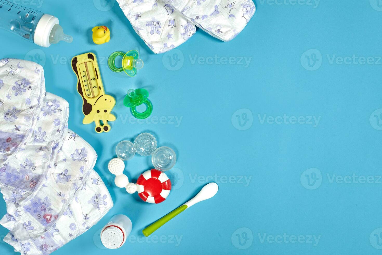 Babies goods cloth diaper, baby powder, nibbler, cream, teether, soother, baby toy on blue background. Copy space. Top view. photo