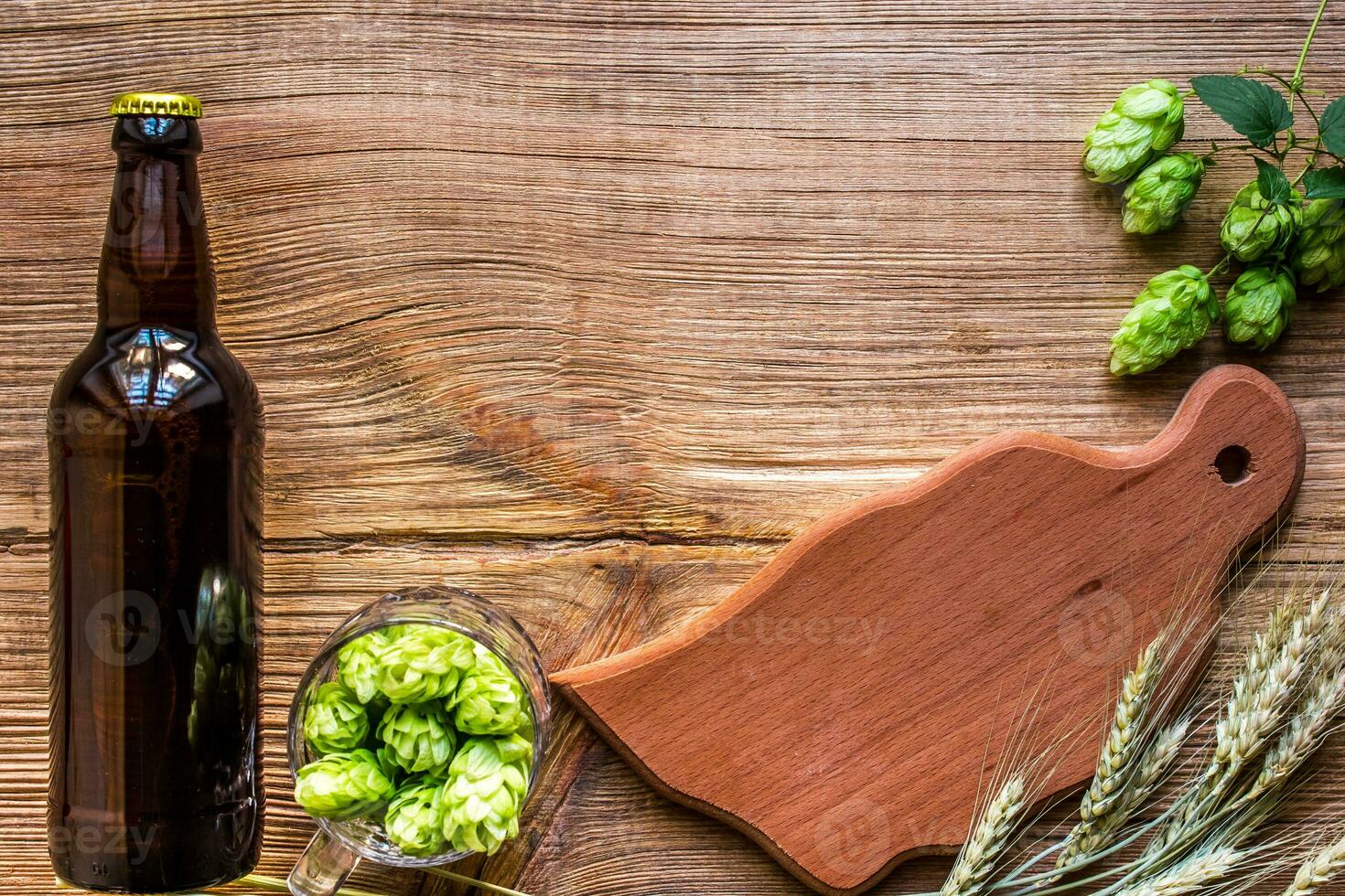 Dark bottle of beer, hops, malt on an old wooden table. photo