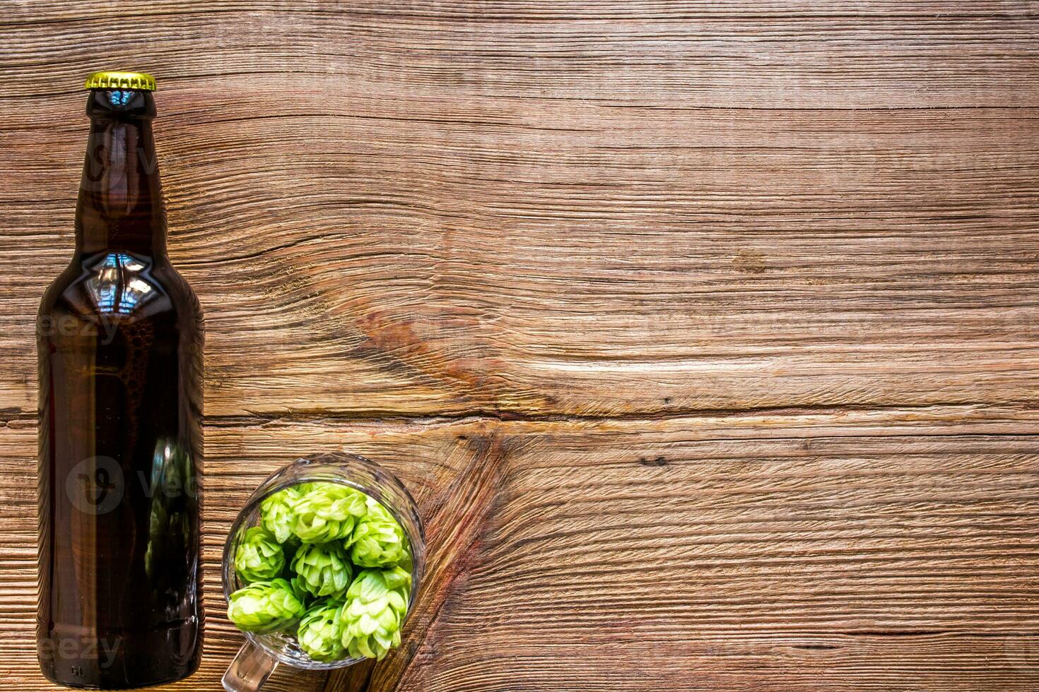 Dark bottle of beer, hops, malt on an old wooden table. photo