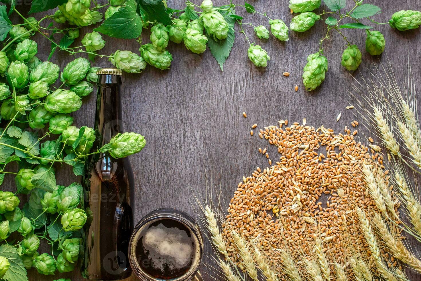 Bottle and glass beer with wheat and hops as brewing ingredients in top view and copy space area photo