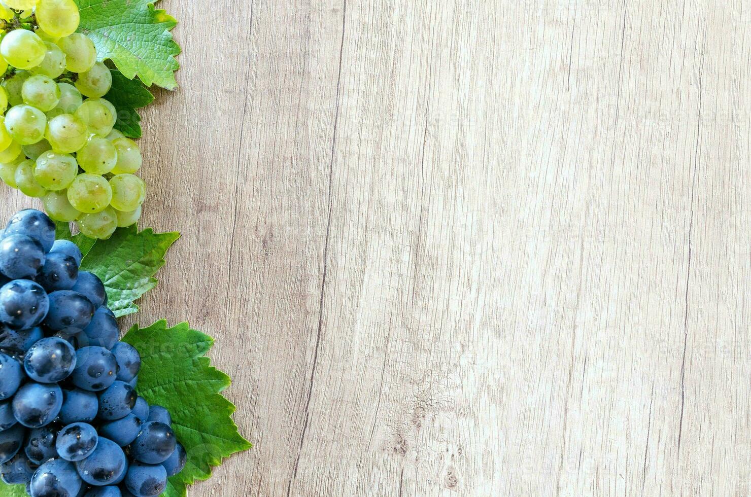 grapes with leaves on wooden background, top view, copy space photo