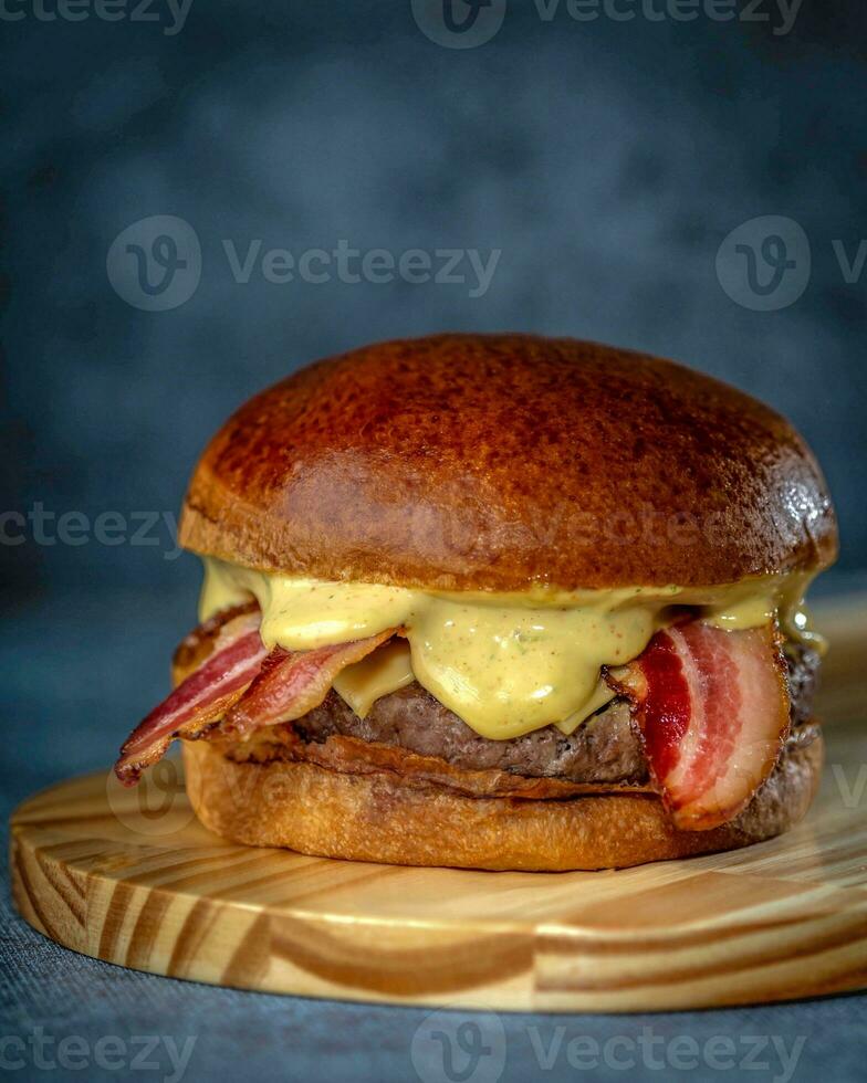 hamburguesa con tocino y queso en un de madera tablero en un oscuro antecedentes foto