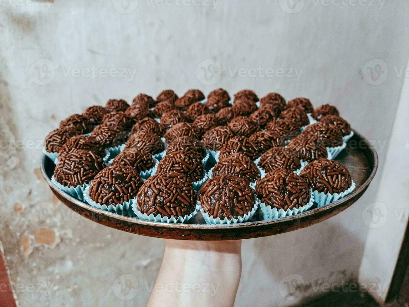 Chocolate truffles on a plate in the hands of a woman photo