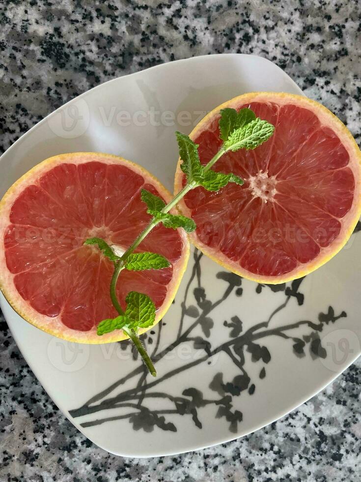 Slices of grapefruit and a sprig of mint on a plate photo