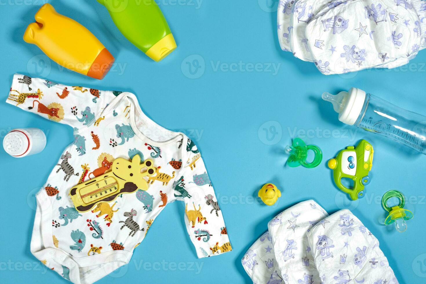 Baby care with bath set. Nipple, toy, clothes, shampoo on blue background top view mockup photo