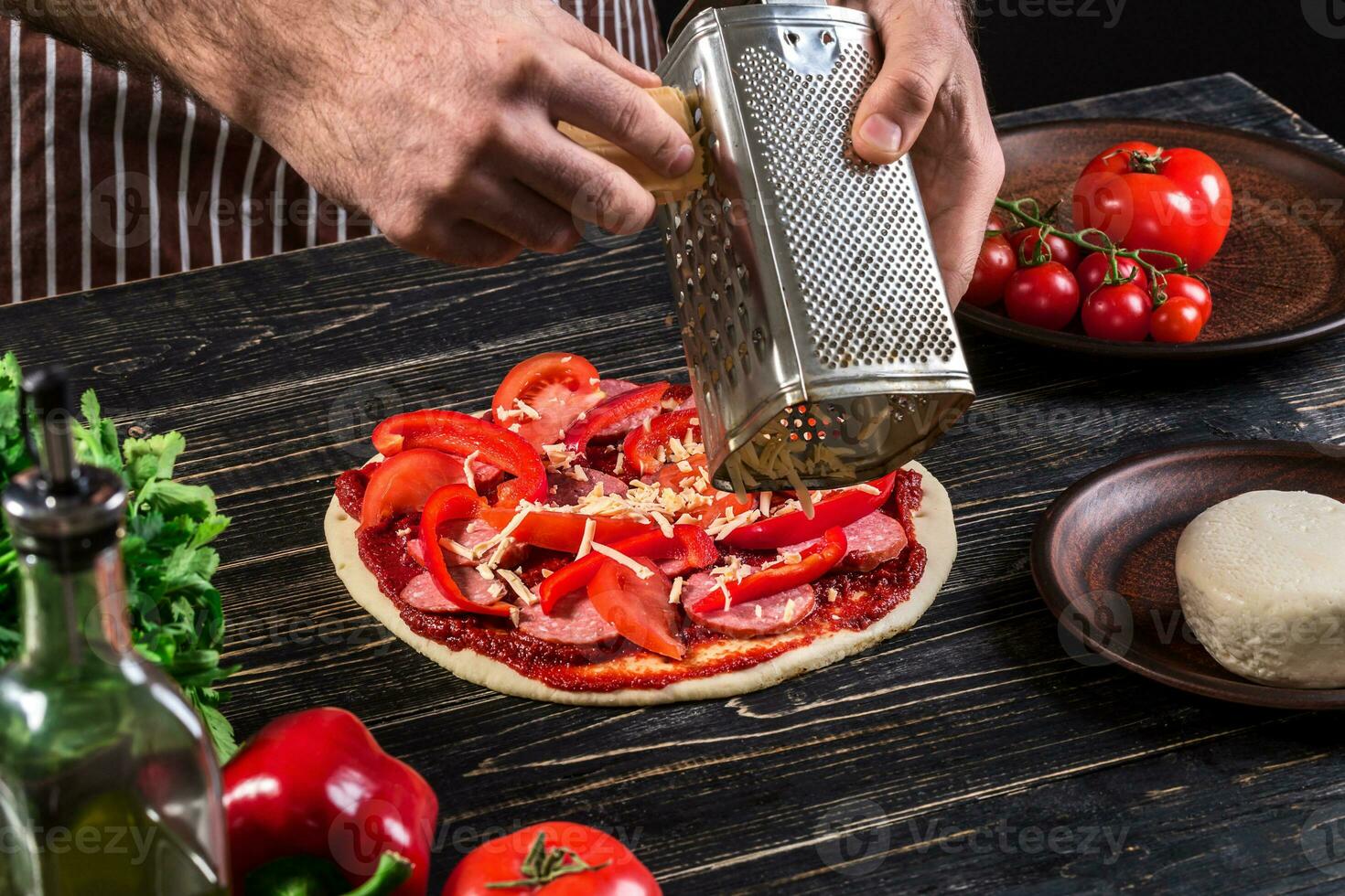 Cook in the kitchen putting the ingredients on the pizza. Pizza concept. Production and delivery of food. photo