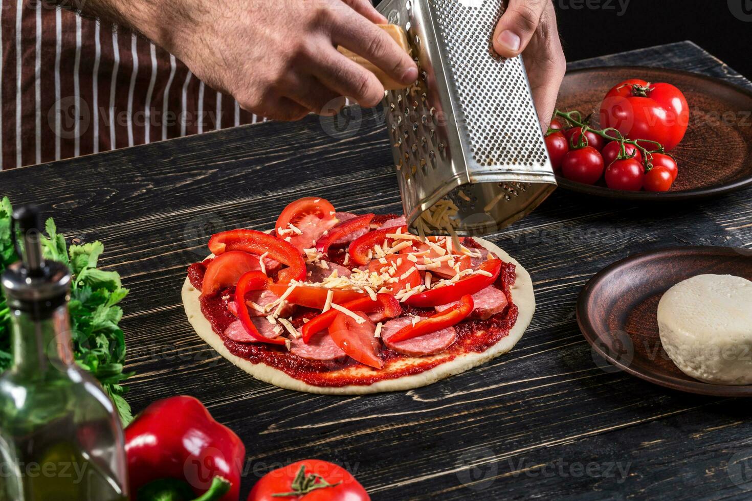 cocinar en el cocina poniendo el ingredientes en el Pizza. Pizza concepto. producción y entrega de alimento. foto