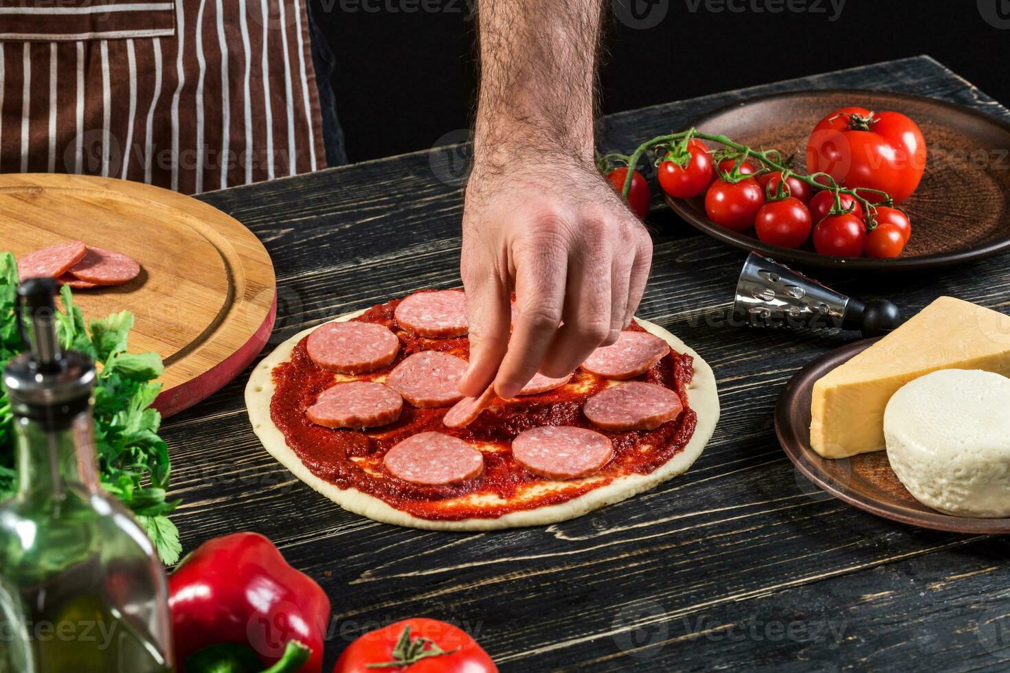 cocinar en el cocina poniendo el ingredientes en el Pizza. Pizza concepto. producción y entrega de alimento. foto