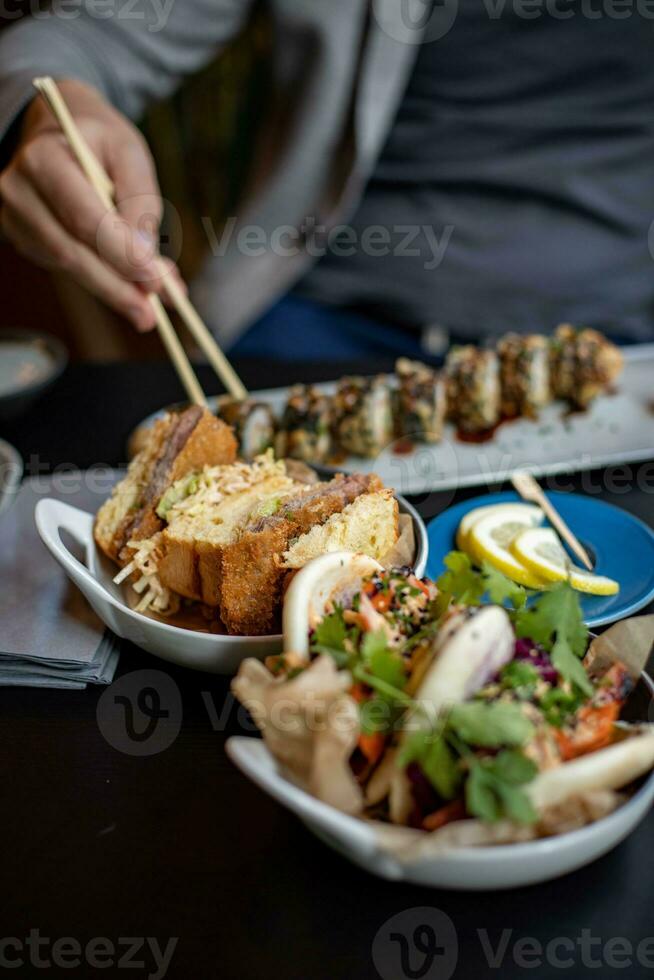 Hands of a man holding a chopsticks over a plate of delicious food photo