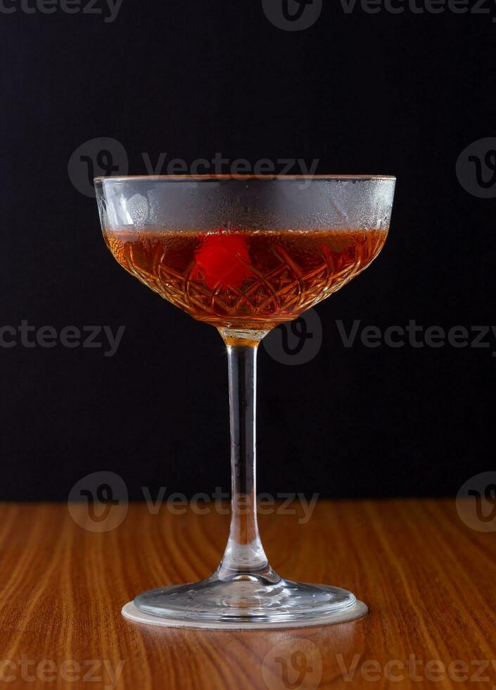 cocktail in a glass on a wooden table on a black background photo