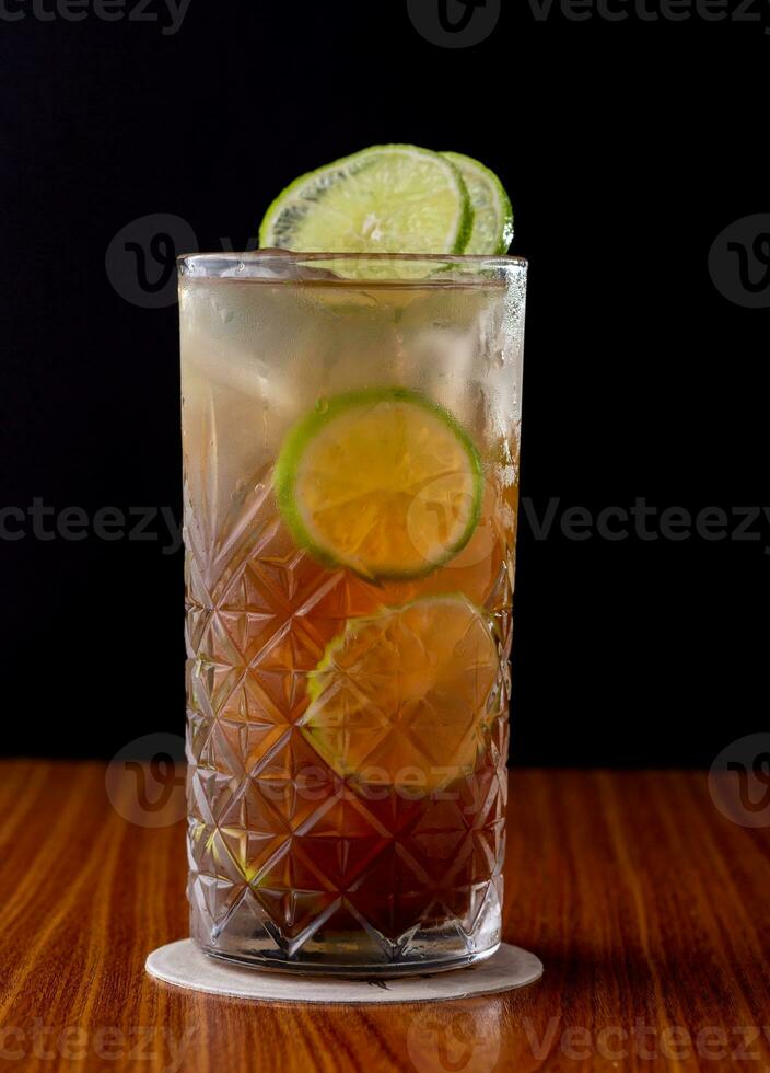 cocktail with lime and ice on a wooden table on a black background photo