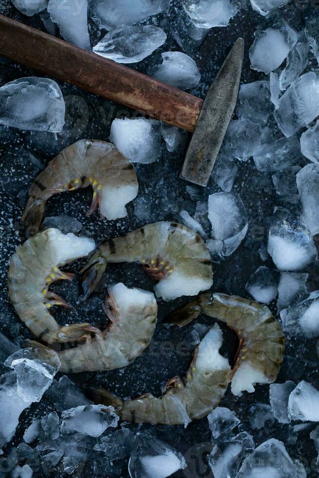 crudo Tigre langostinos en hielo con un martillo. parte superior vista. foto
