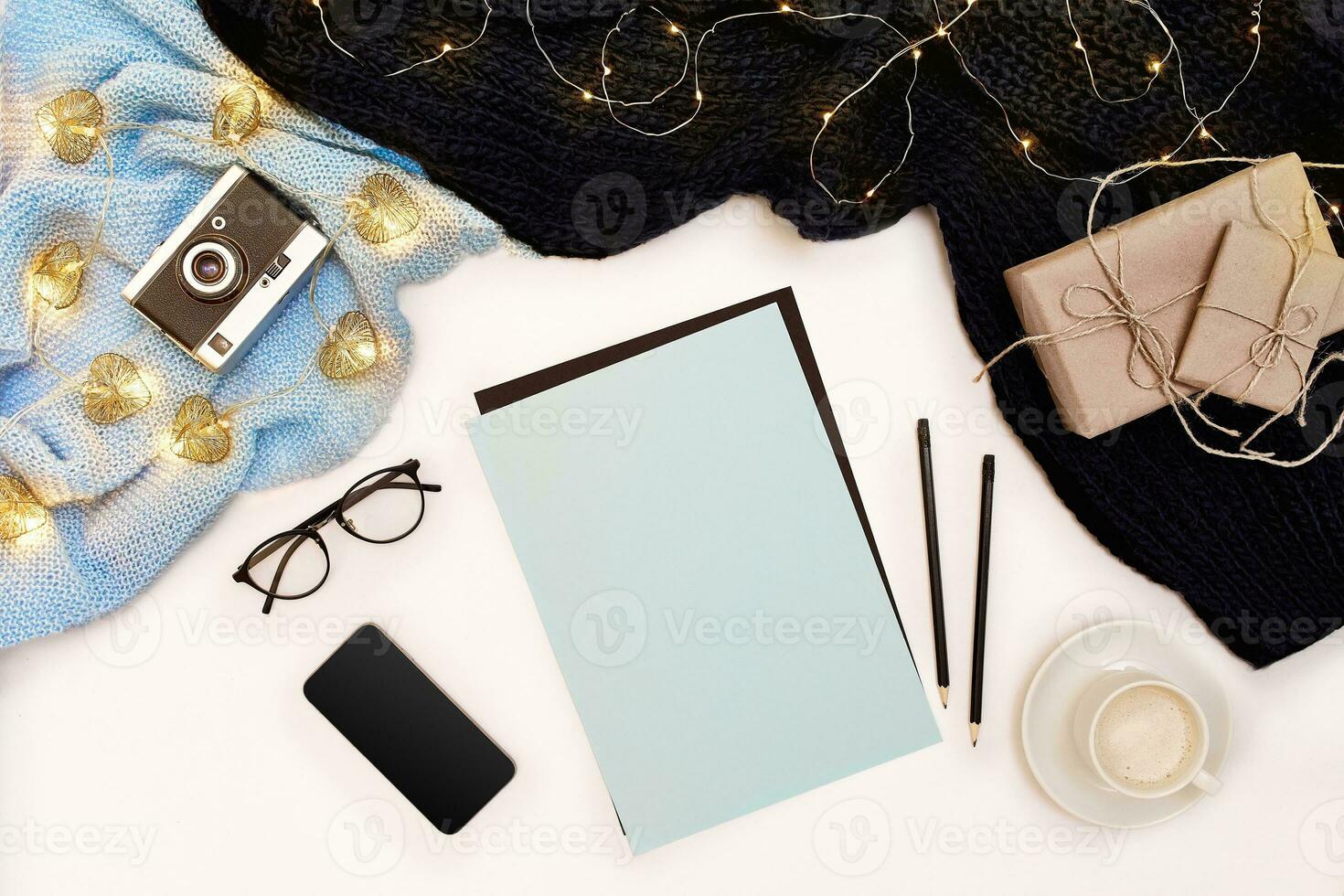 Open clean notebook for your text, pen, gift boxes, scarf and Christmas lights on white background, top view. photo