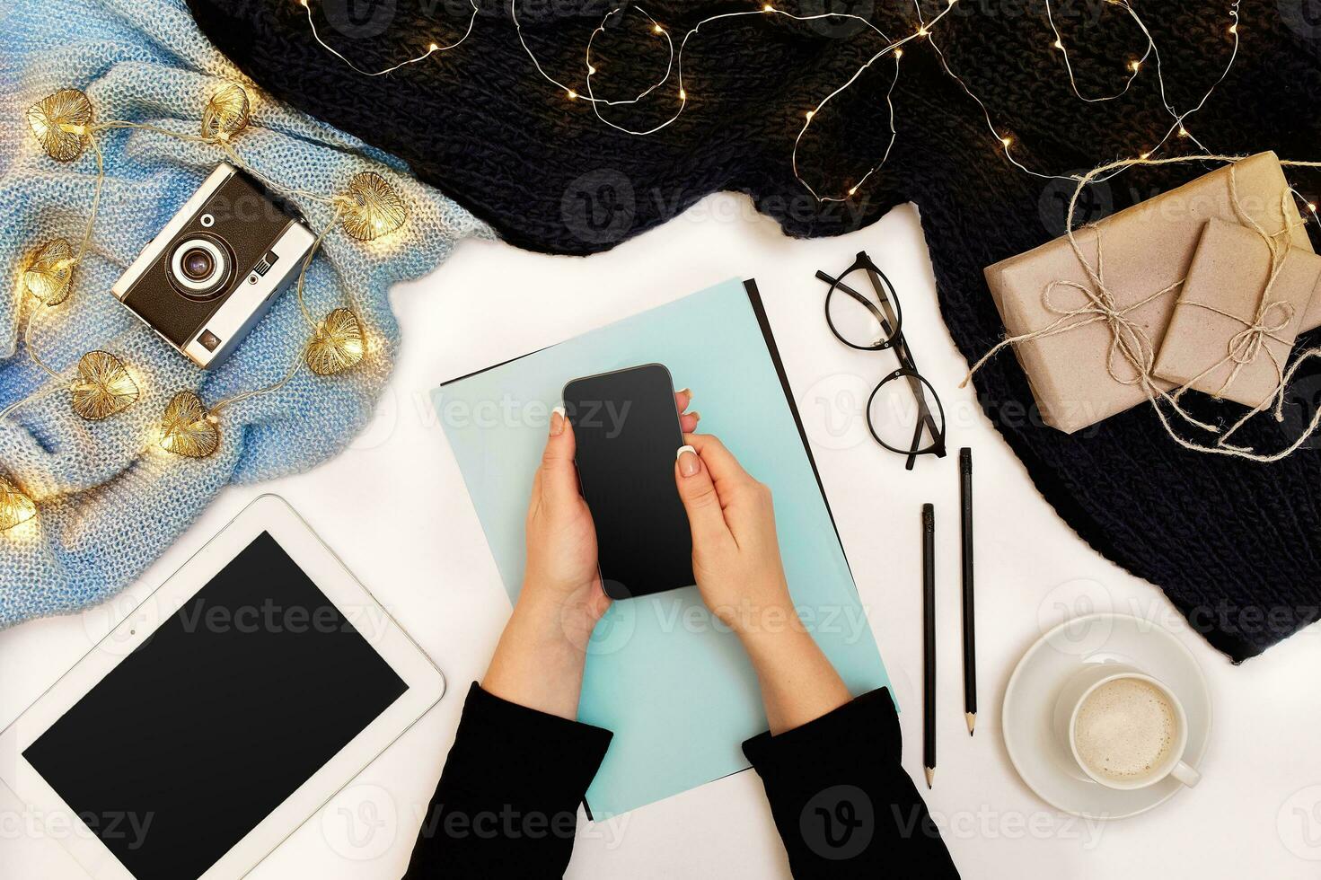 Top view,close-up of tablet computer with blank screen in hands of woman dressed in knitted sweater. Nearby is cup of coffee and scarf photo