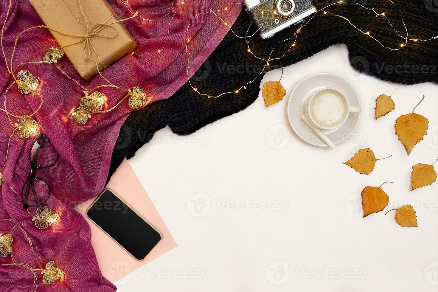 Romantic autumn mock up. Sheet of pink paper, smart, yellow and orange leaves, pencils, cup of cappuccino and old camera.Top view. Flat lay. photo