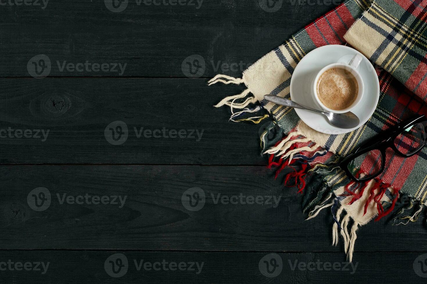 White cup of the coffee and vintage scarf on black wooden background photo