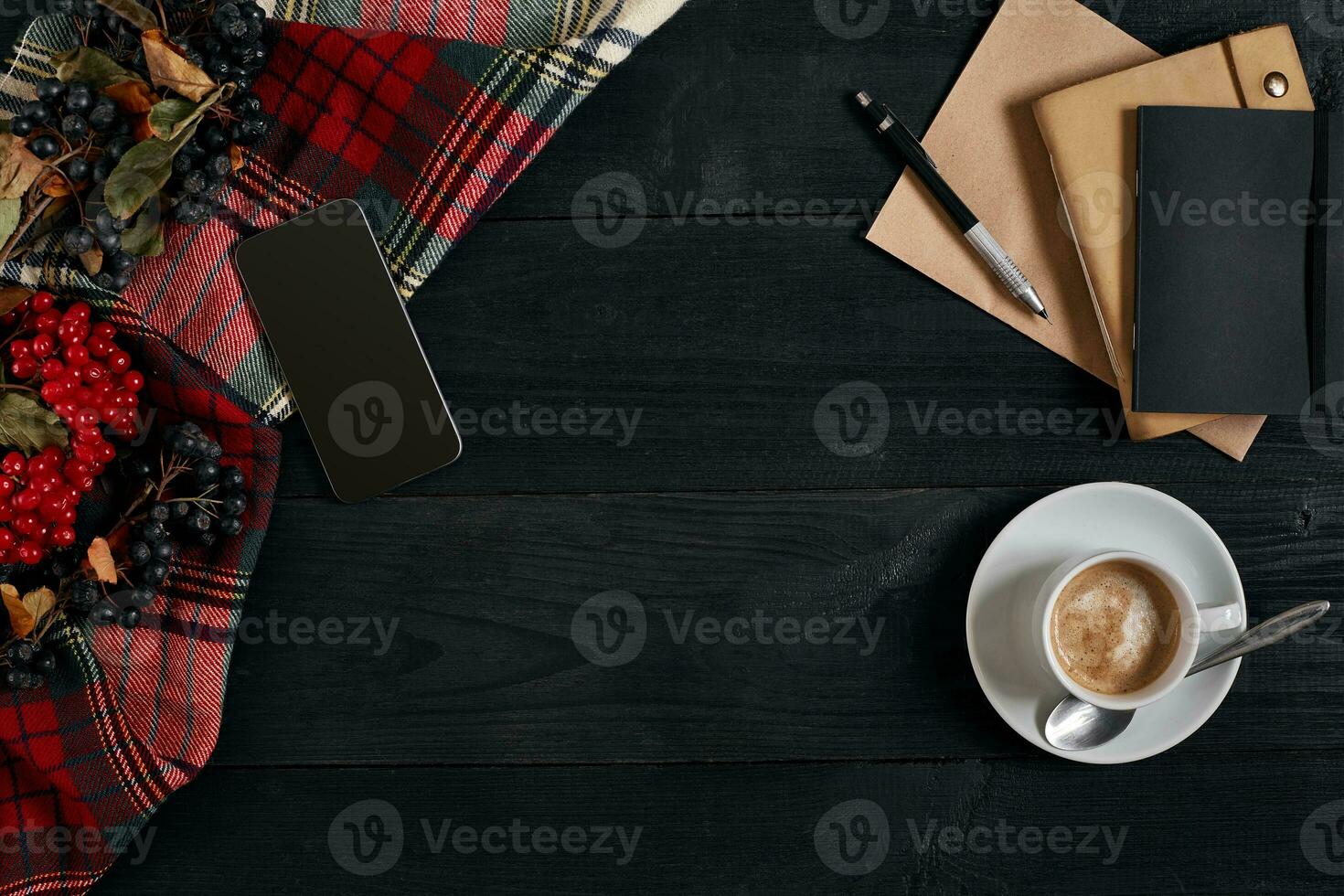 Above view of Smart phone with notebook and cup of latte coffee on black wooden background. photo