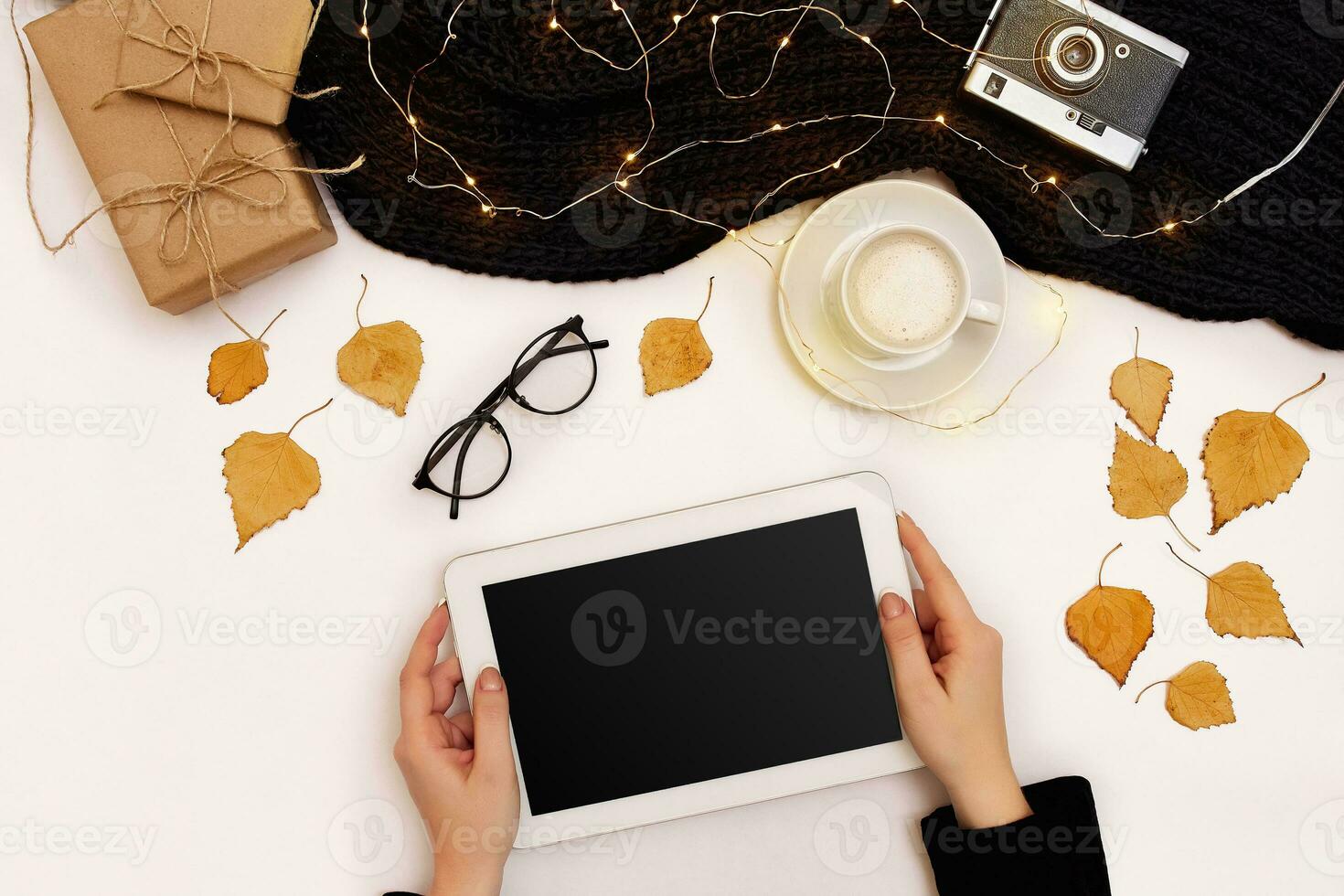 Top view,close-up of tablet computer with blank screen in hands of woman dressed in knitted sweater. Nearby is cup of coffee and scarf photo