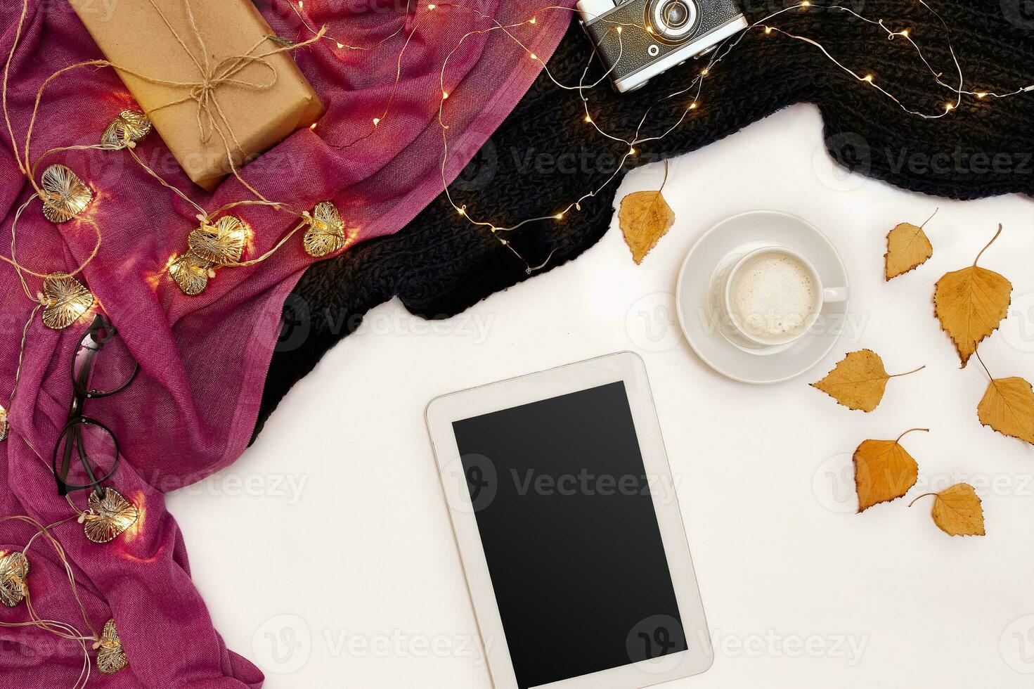 Autumn concept, dried fall leaves, mug of cocoa, old camera, scarf and tablet with blank screen. Mock up photo