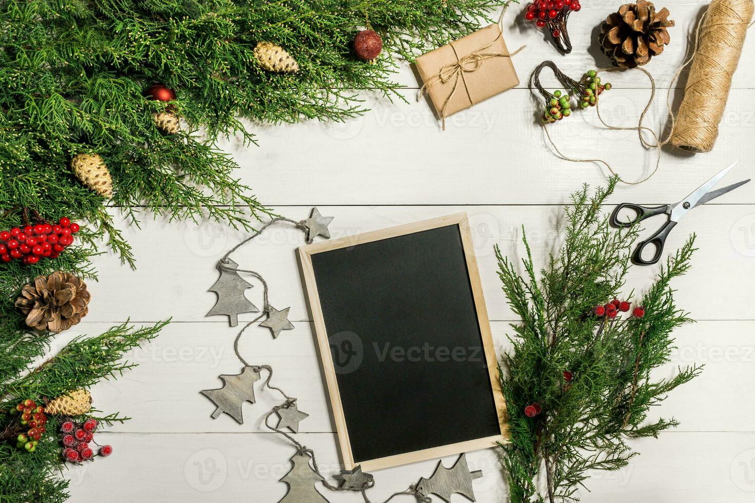 Juniper branches with a Christmas decor. Christmas, New Year background. Coniferous branches of juniper and black writing board. Top view, flat design. photo