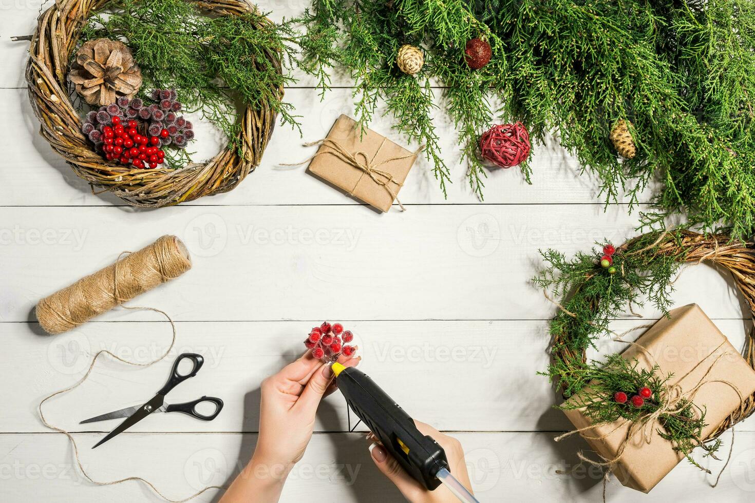 Christmas handmade diy background. Making craft xmas wreath and ornaments. Top view of white wooden table with female hands. photo