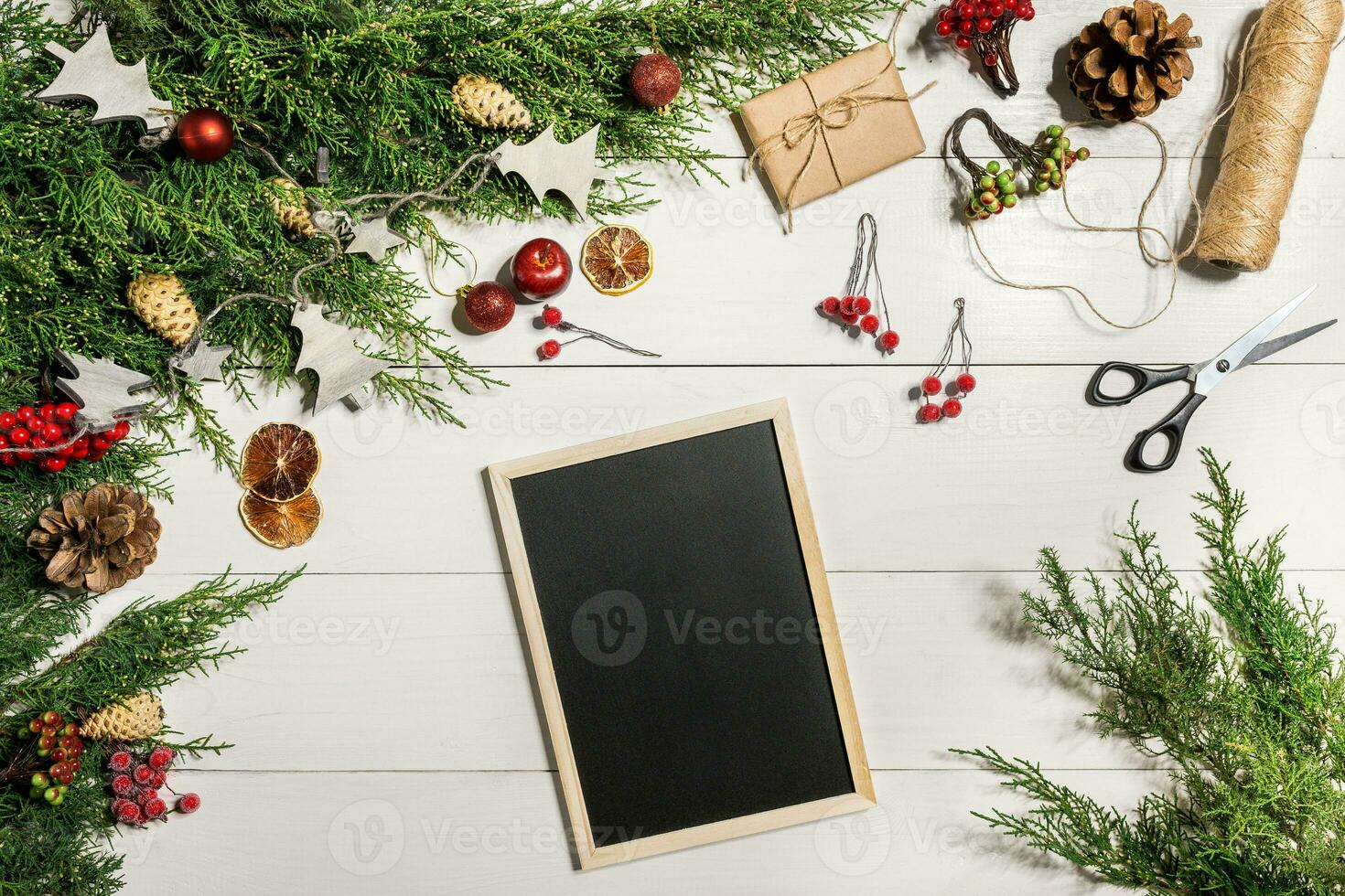 Juniper branches with a Christmas decor. Christmas, New Year background. Coniferous branches of juniper and black writing board. Top view, flat design. photo