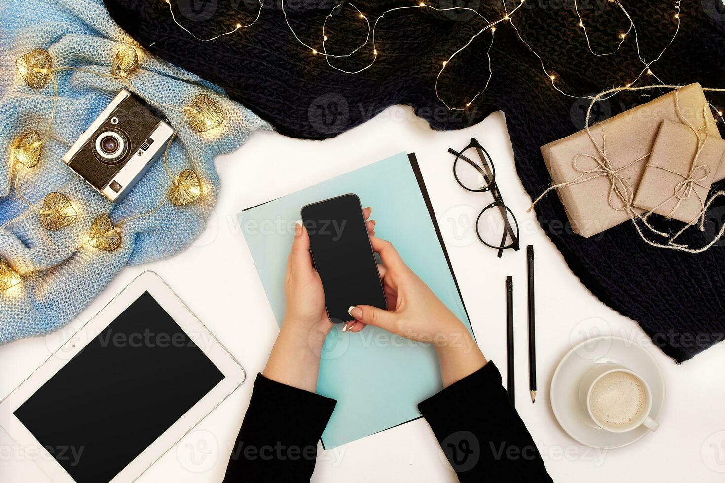 Top view,close-up of tablet computer with blank screen in hands of woman dressed in knitted sweater. Nearby is cup of coffee and scarf photo