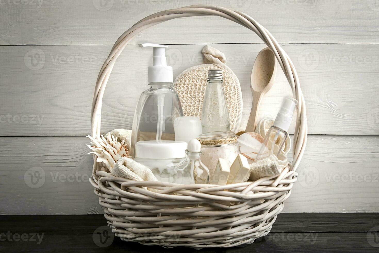 Composition of cosmetic bottles and soap in basket, on white wooden background photo