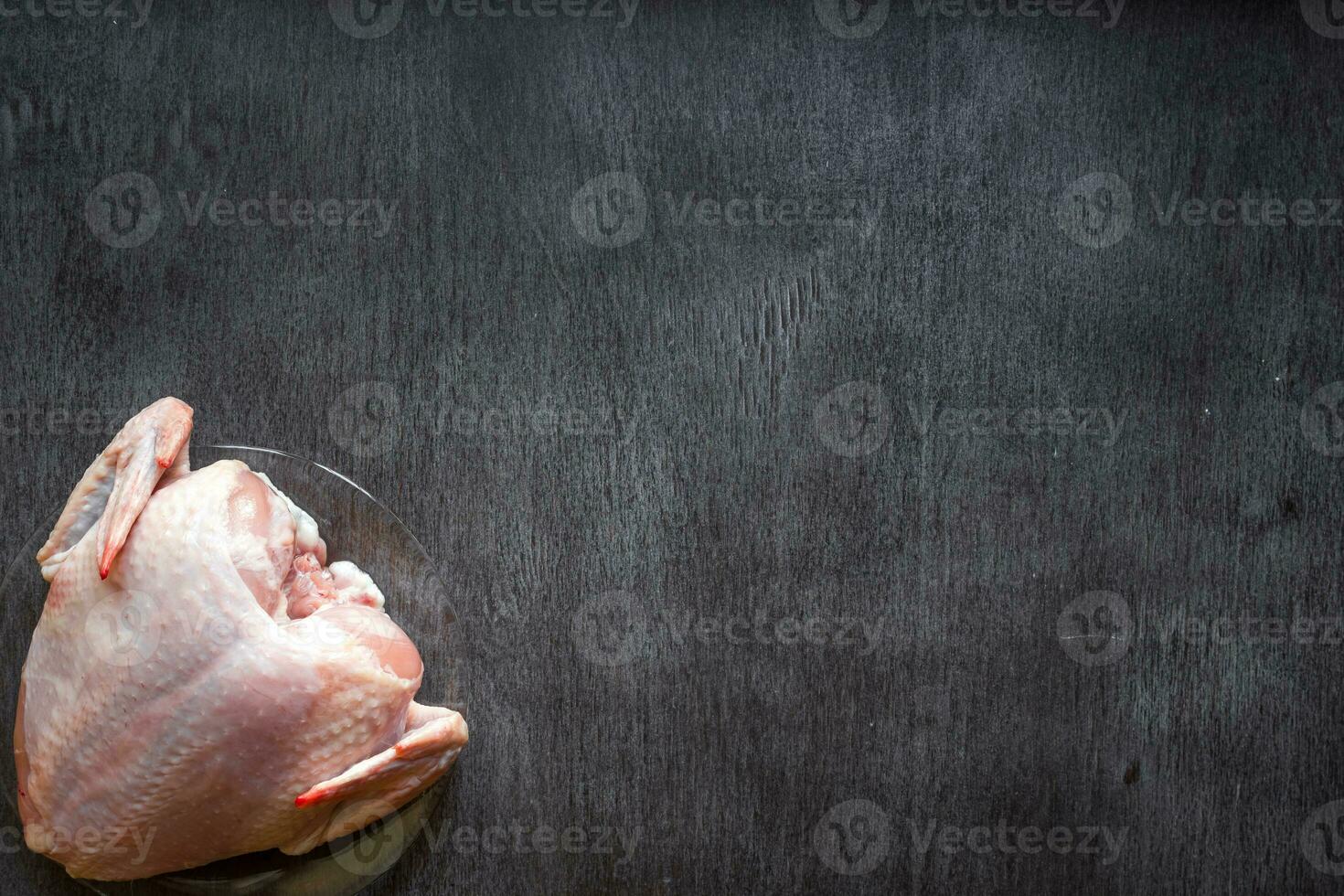 Whole raw chicken on a wooden table photo