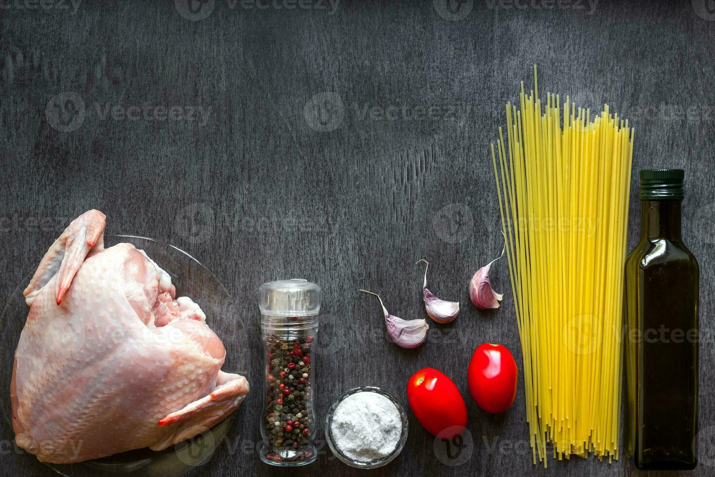 Pasta ingredients. Chicken breasts, Cherry tomatoes, spaghetti pasta, oil, spices and garlic on the wooden table. Space for text. photo