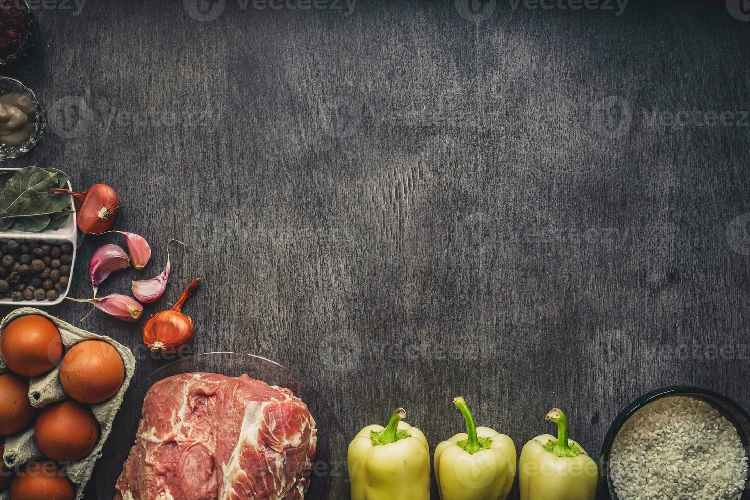 Raw pork meat on a dark wooden surface and ingredients for cooking. Food background with copy space. photo