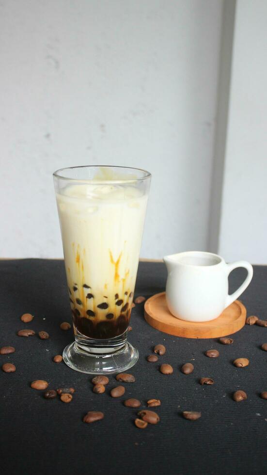 milk coffee in a glass containing boba on a white and black background photo