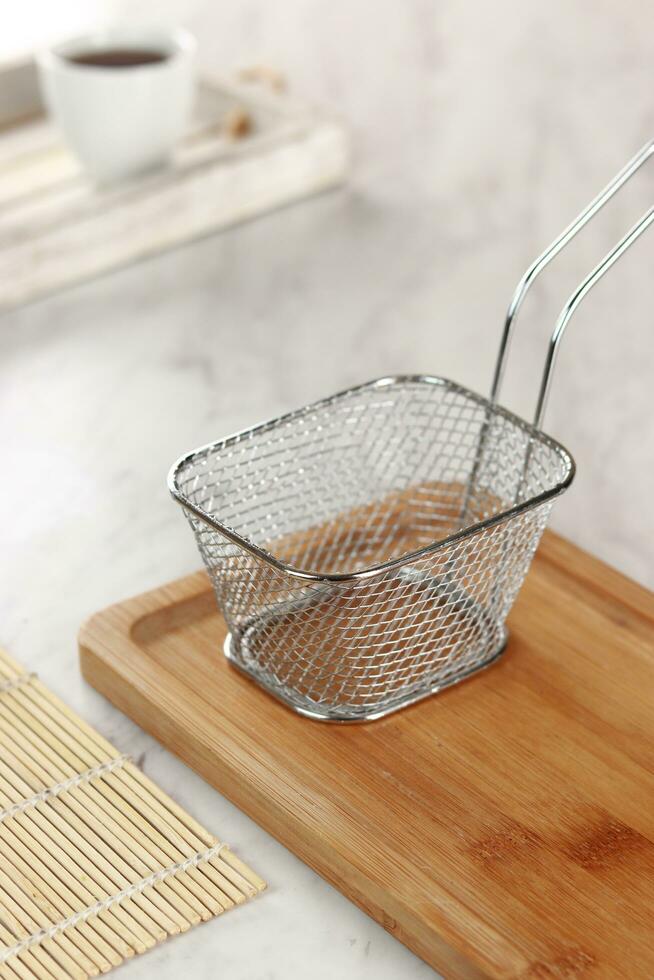 side view of empty stainless steel wire chip serving basket isolated on wood background texture photo