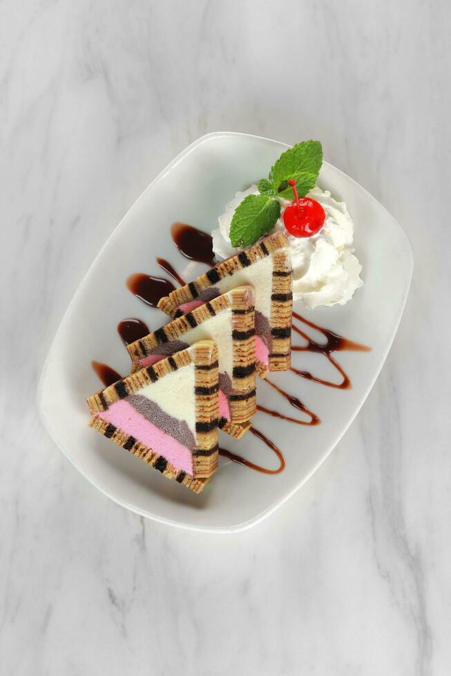 white, chocolate and pink ice cream with layer cake and ice cream. served on a small white plate. isolated in white background photo