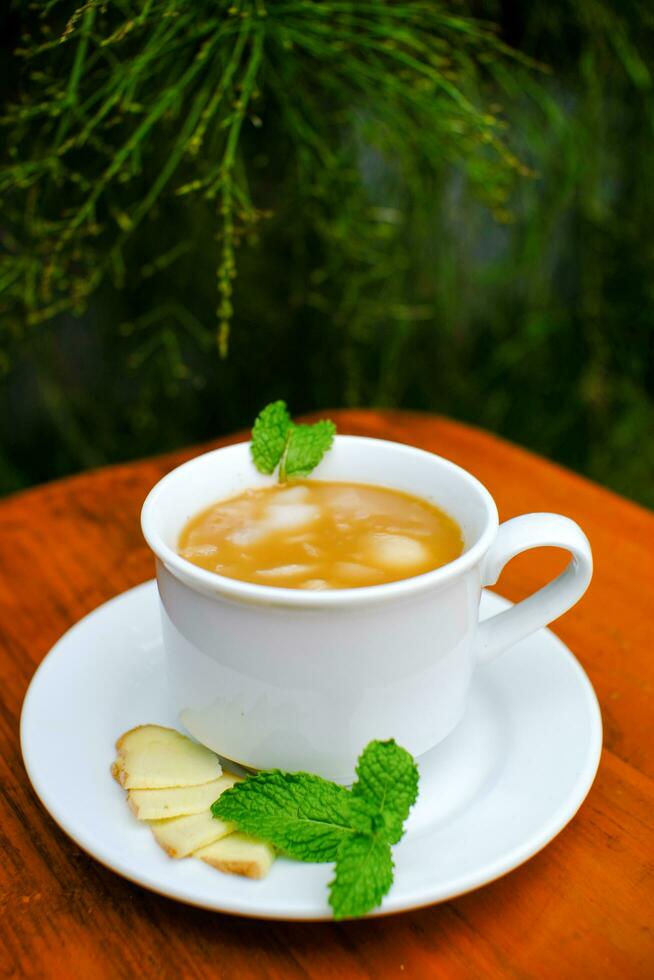 glass mug of hot ginger drink while wrapped in blanket. Close up shot photo