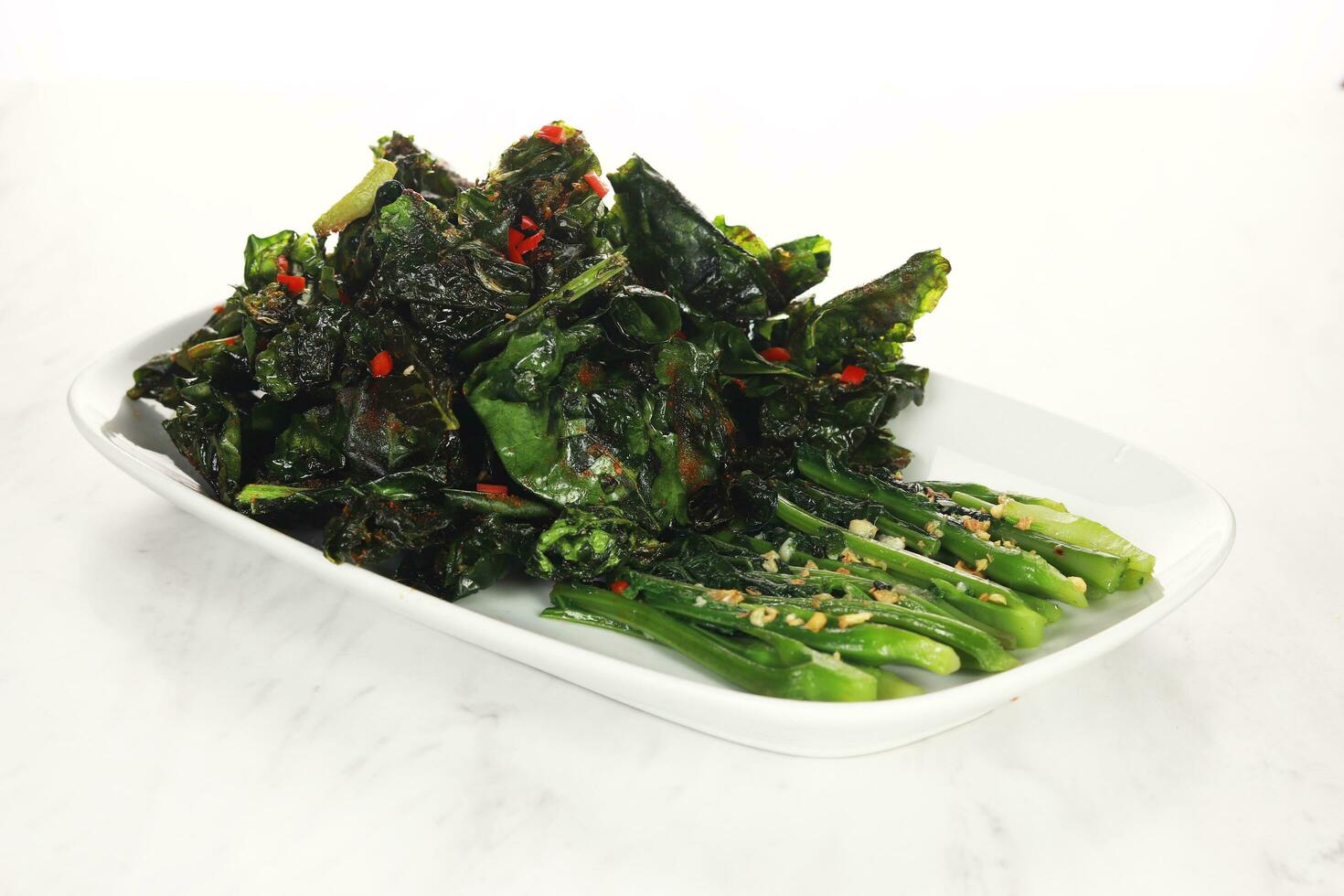 fried cooked green vegetables called kailan are served on a white plate. isolated on solid white background photo