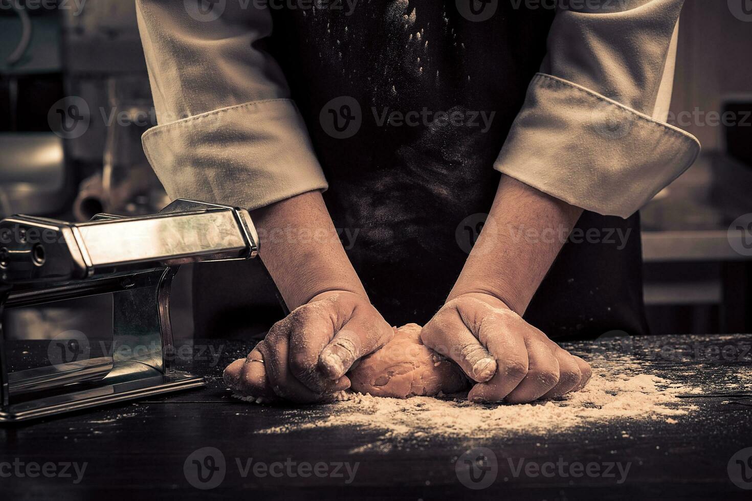 The chef makes dough for pasta on a wooden table photo