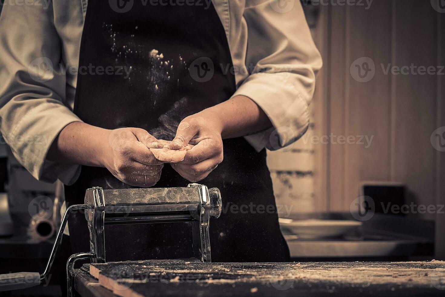 The chef makes dough for pasta on a wooden table photo