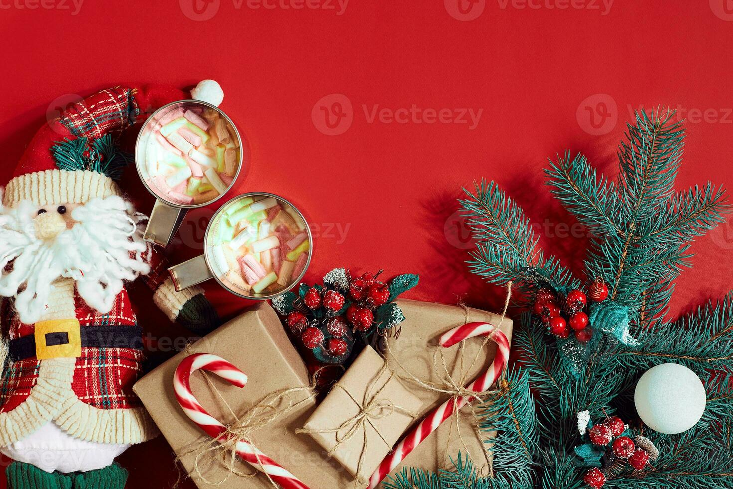 Fir branch, gift box and two cups of cocoa with marshmallows on red background photo