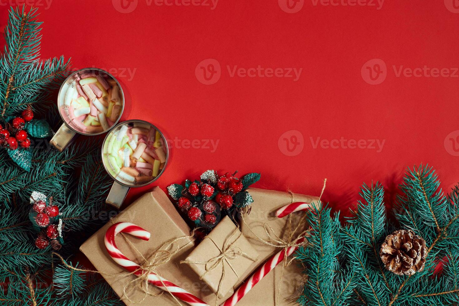 Fir branch, gift box and two cups of cocoa with marshmallows on red background photo