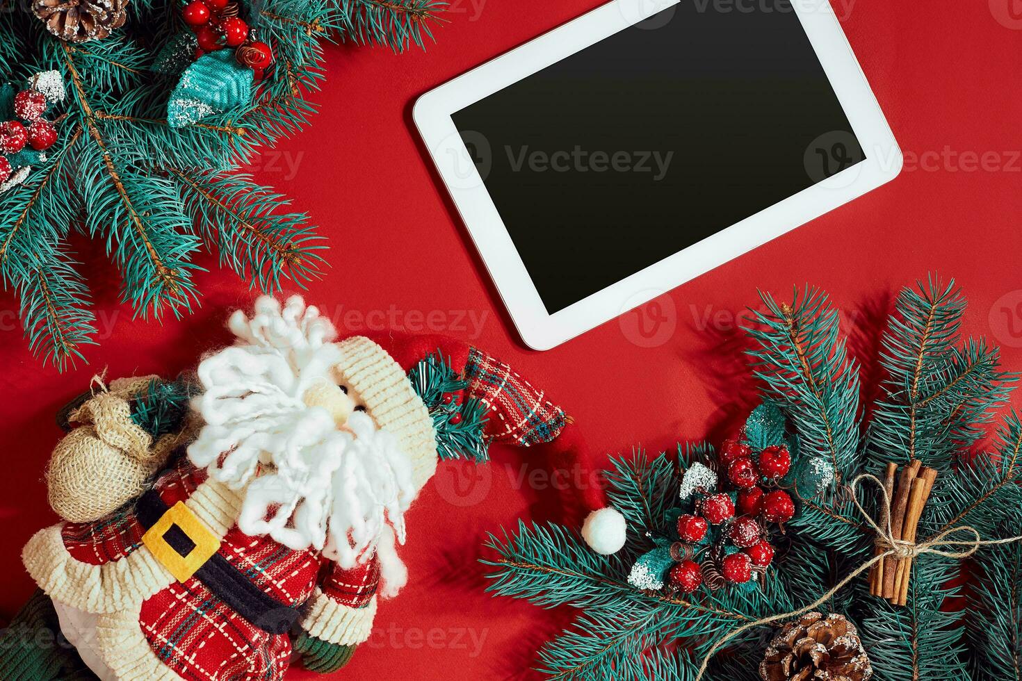 Christmas decorations and white tablet with black screen on hot red background. Christmas and New Year theme. Place for your text, wishes, logo. Mock up. photo