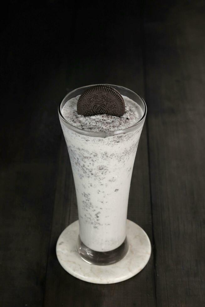 milkshake with whipped cream and biscuits served in glass on the light gray table. isolated in white and dark wood background photo
